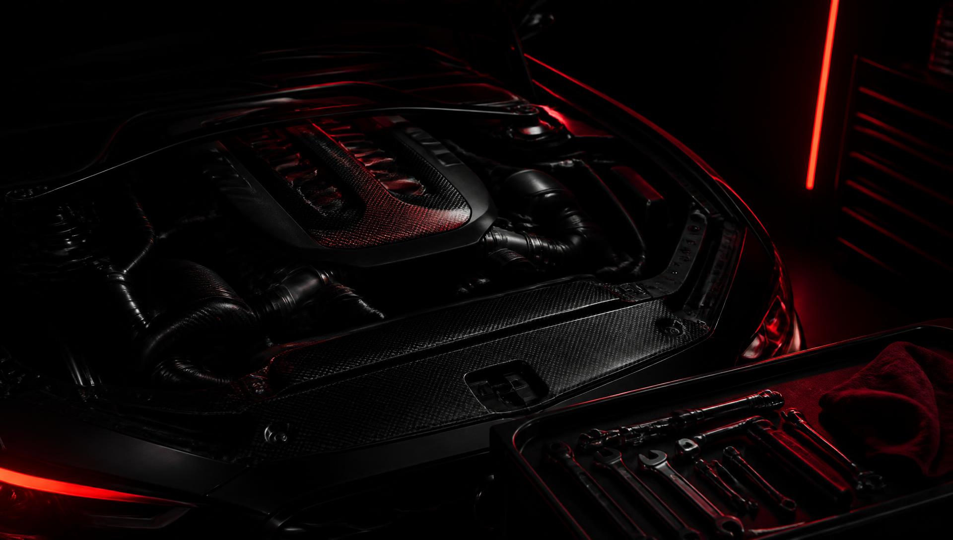Engine bay of a modern vehicle lit in red inside a professional garage